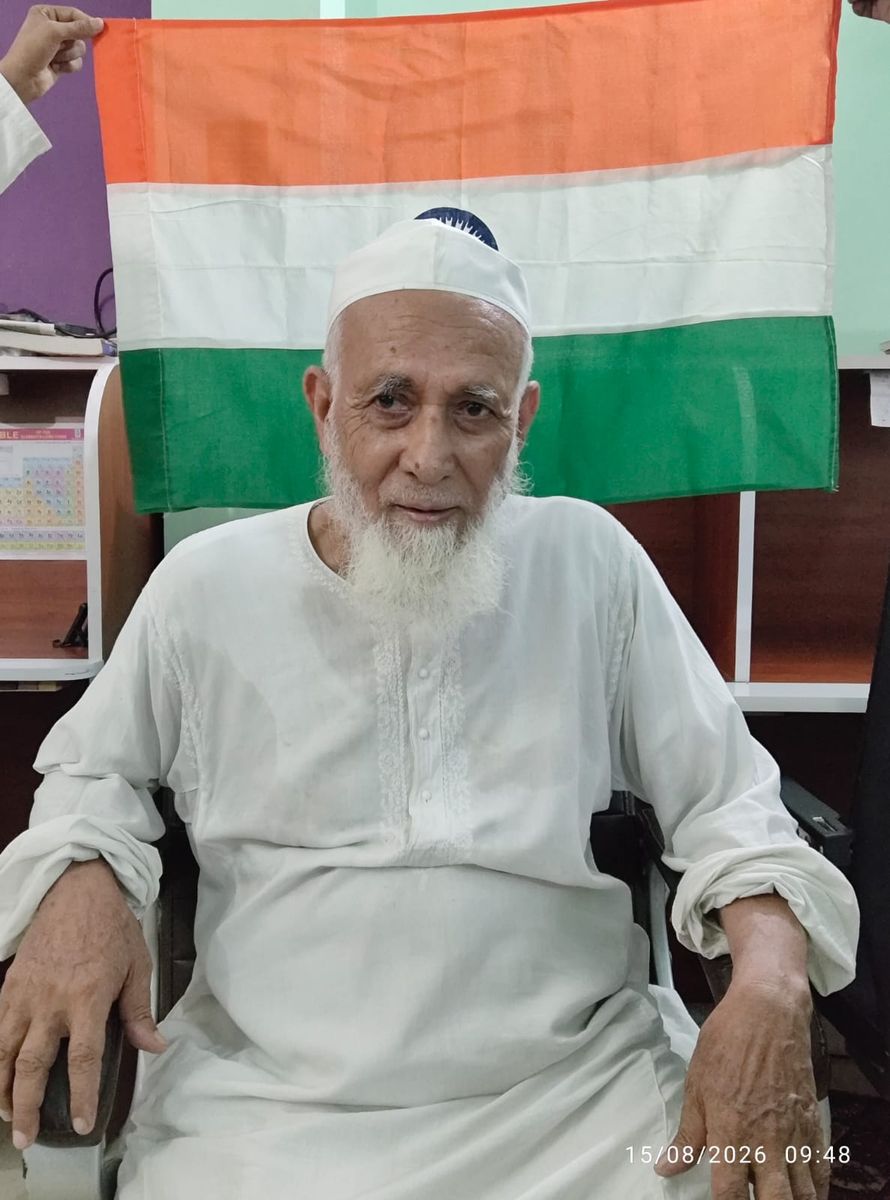 Senior member seated in front of the Indian flag at the library